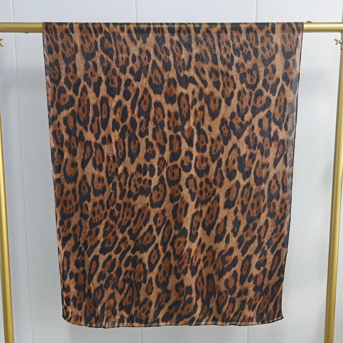 Braun-schwarzer Leopardenmuster-Schal auf goldener Kleiderstange