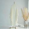 A white ruffled two-layer chiffon hijab displayed on a hanger against a light background next to dried pampas grass.