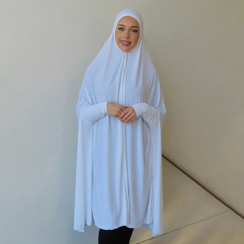 Eine Frau trägt eine elegante weiße Baumwoll-Abaya mit Ärmeln und passender Hijab.