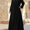Une femme portant une élégante robe longue noire ample avec un col montant.