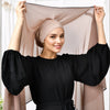 Eine Frau modelliert einen durchscheinenden beige Chiffon-Hijab und ein schwarzes Langarm-Top mit Schleifdetail.