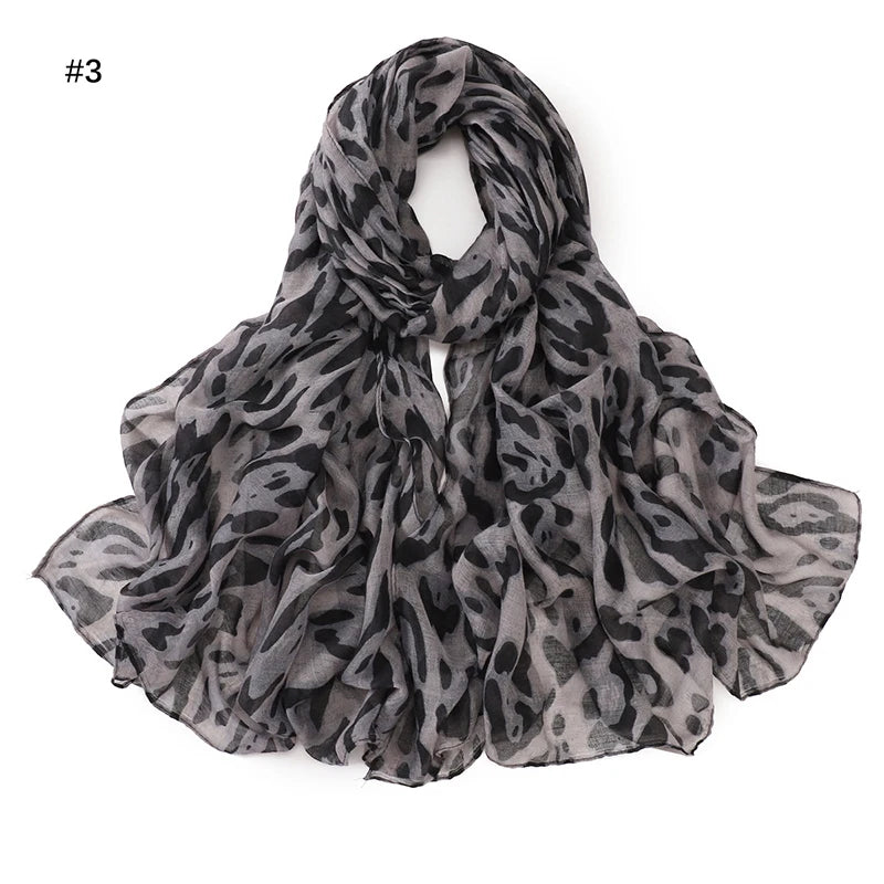 Écharpe pashmina à motif léopard gris foncé, drapée et pliée pour exposition.