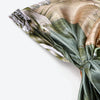 Gros plan d'un foulard instant en satin imprimé avec un motif floral olive terne et beige.