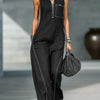 Una modelo vistiendo un top de punto negro sin mangas y pantalones a juego con joyas plateadas.