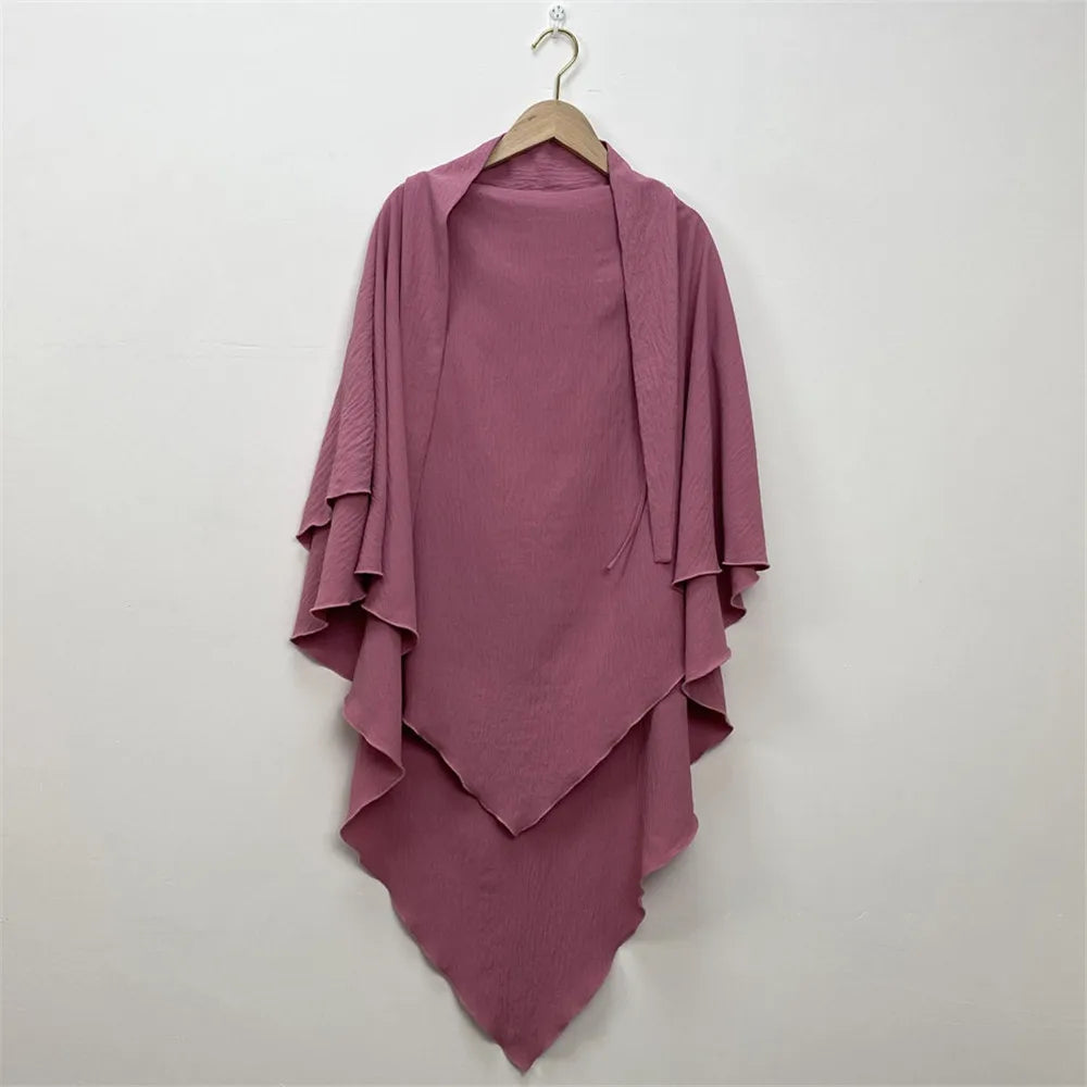 A mauve two-layer everyday hijab scarf draped on a wooden hanger against a white wall.