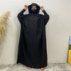 Une personne portant une abaya noire avec capuche et manches batwing, de face.