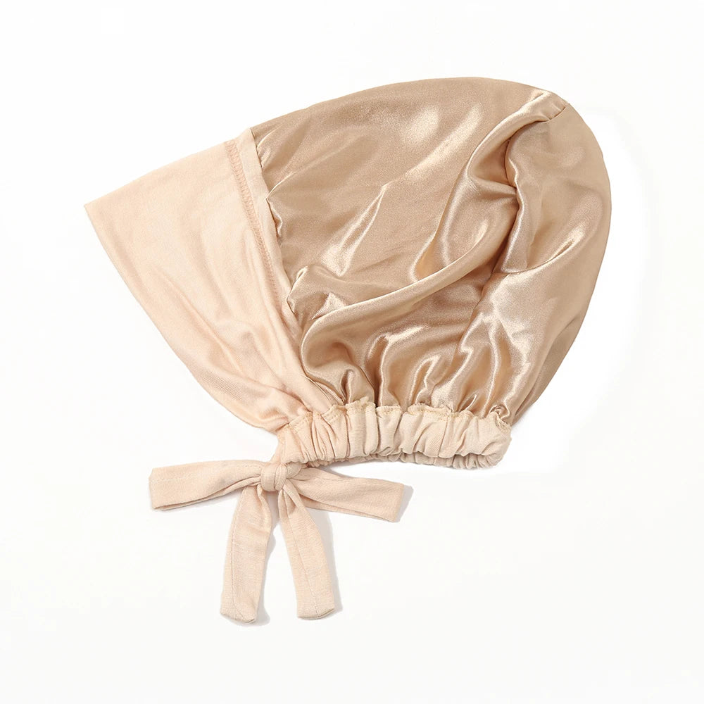 A beige satin hijab cap and undercap set with a gathered fabric top and tied bow detail.