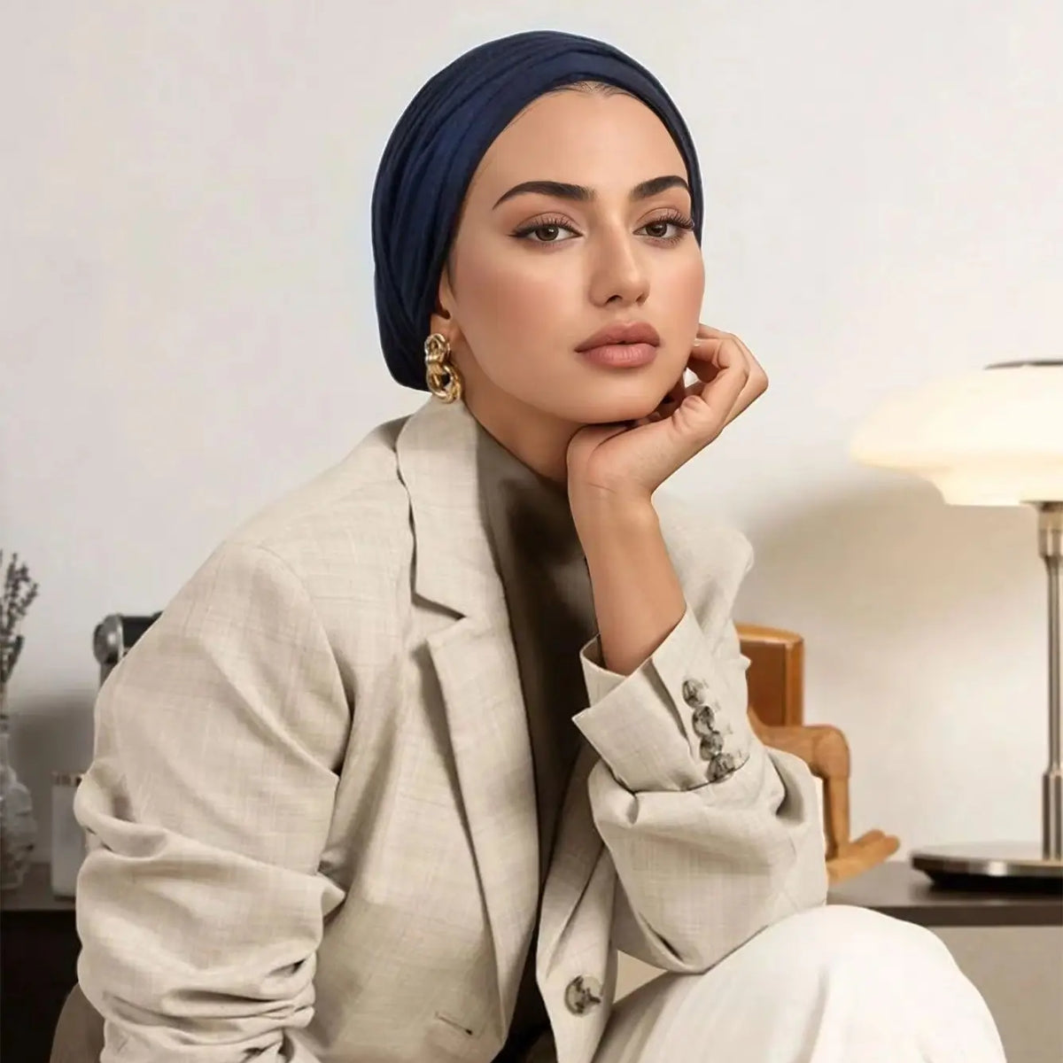 Une femme portant un blazer beige et un instant hijab bleu marine, gros plan.