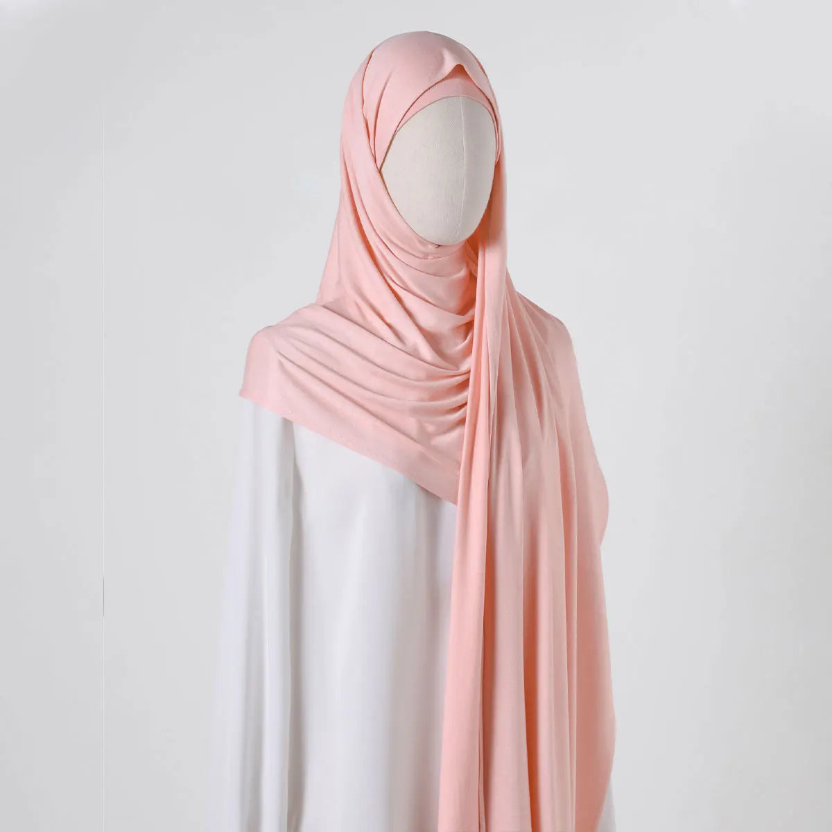 Eine Frau trägt einen rosa Chiffonschal über ein weißes Kleidungsstück.