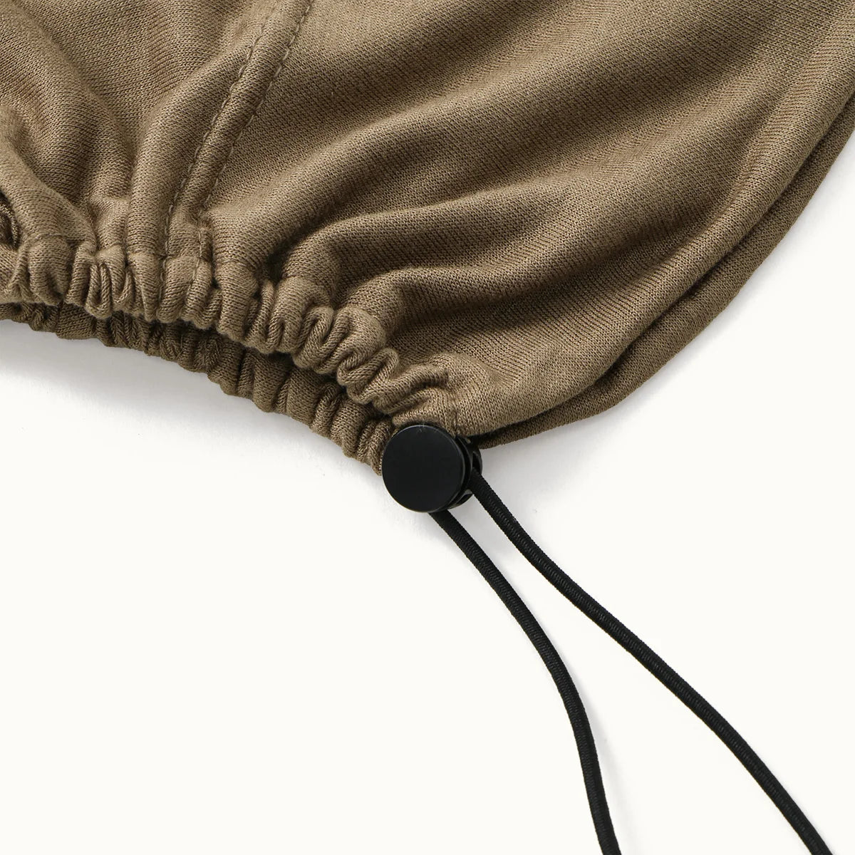 A close-up of a beige adjustable modal hijab cap with elastic bands and black drawstrings.