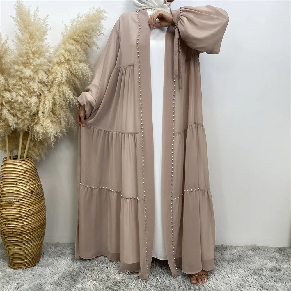 Cardigan abaya de cuentas beige usada por una modelo contra un fondo blanco.