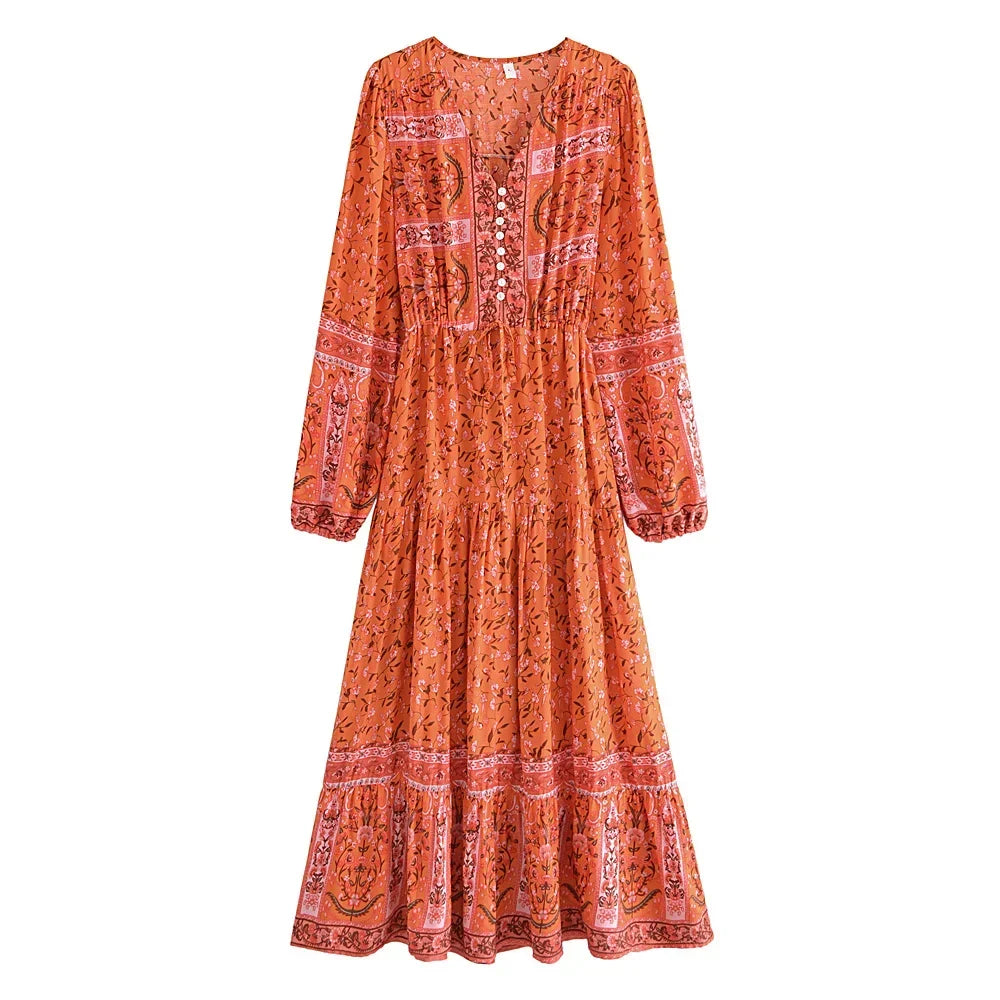 An orange floral lantern sleeve maxi dress with intricate embroidery and a tiered skirt.