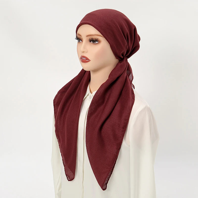 A model is wearing a solid maroon linen elastic headscarf cap with a white top.