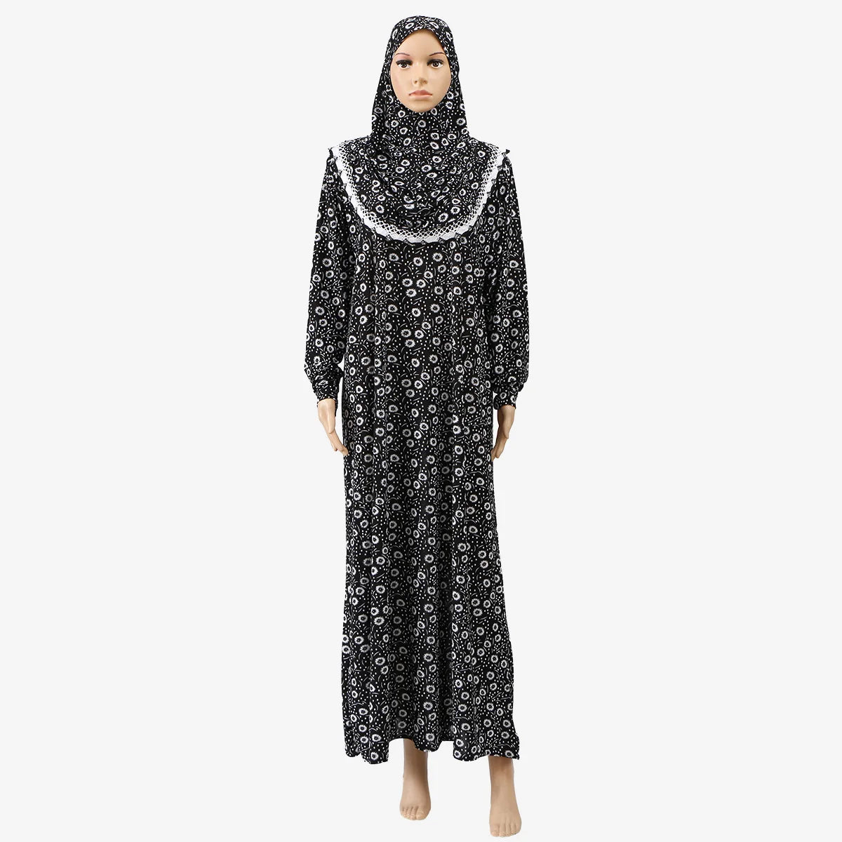 A woman wearing an elegant black and white patterned Muslim hijab dress for prayer and daily wear.