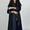 Eine Frau trägt ein elegantes schwarzes Polka-Dot-Abaya-Cardigan-Kleid mit dunkler Kleidung und goldenen Schmuck.