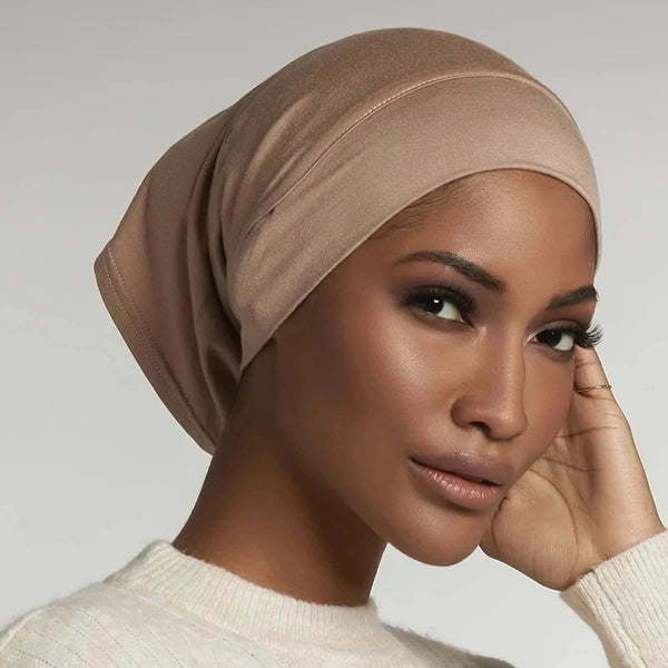 A close-up of a woman wearing a beige soft stretch cotton modal hijab bonnet.