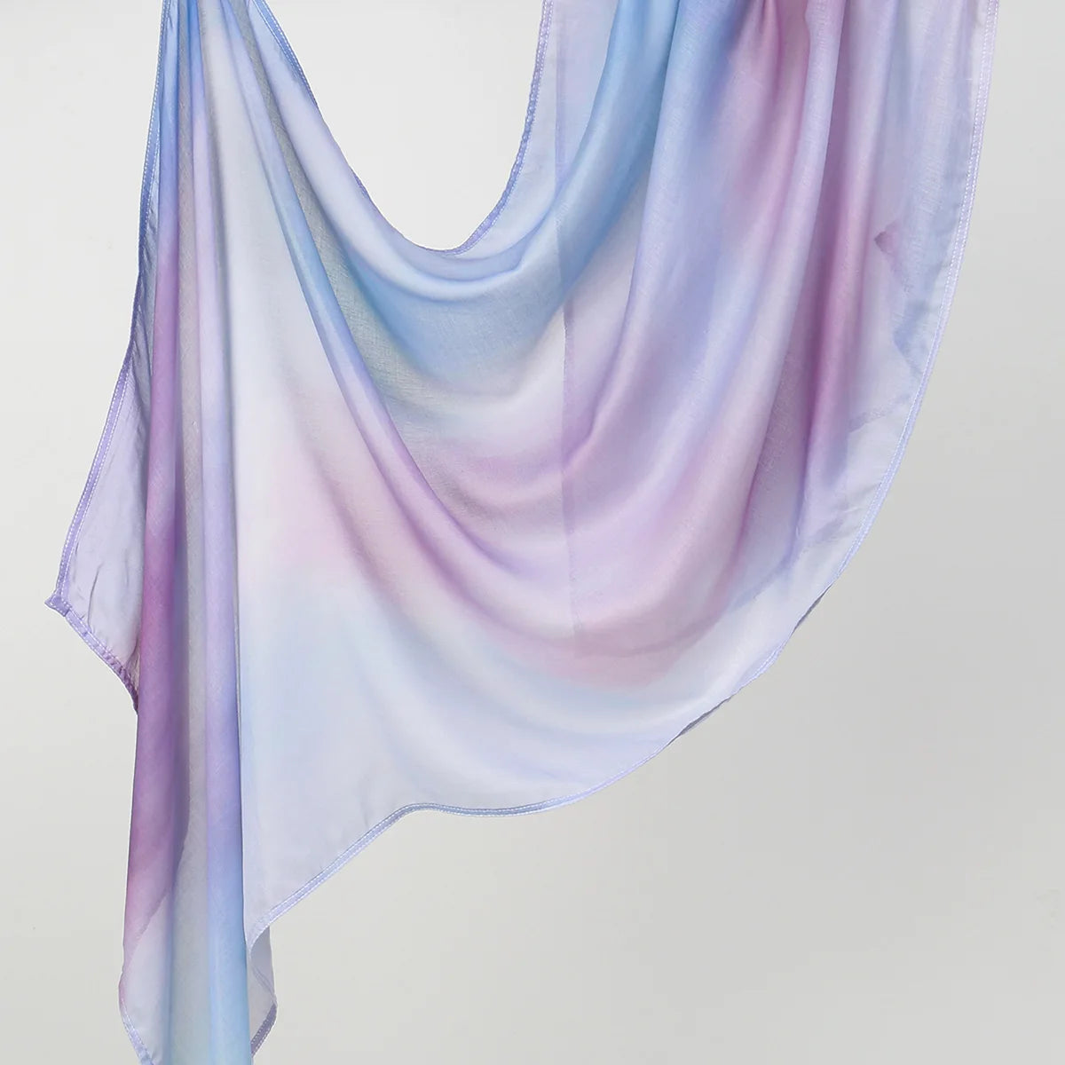 Fließender, durchscheinender Hijab-Schal in sanften Lavendel- und Blautönen elegant drapiert.
