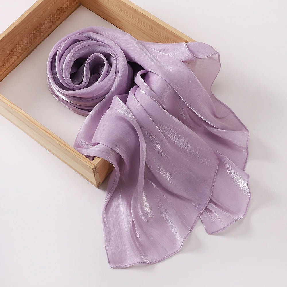 Étole légère et scintillante de chiffon crinklé lilas drapée dans un pli lâche dans un cadre en bois.