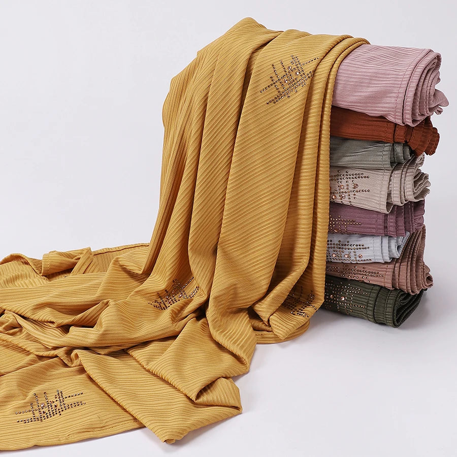 Senfgelber gerippter Jersey-Hijabschal, gefaltet und gerollt, zeigt verschiedene Rosa- und Beige-Töne.