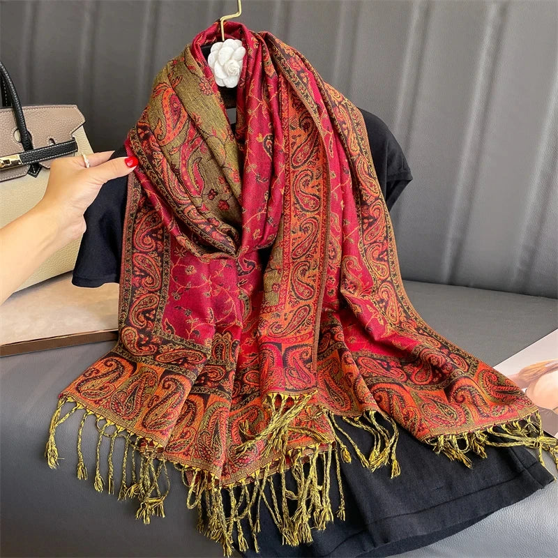 Pashmina de lujo roja y naranja con patrón, drapeada sobre una prenda negra.