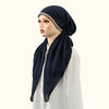 Une femme portant un foulard modal bleu marine avec des incrustations de diamants et un haut blanc.