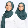 Eine Frau trägt einen eleganten, einfarbigen Chiffon-Hijabschal in gedämpftem Grün.
