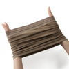 A close-up of a brown adjustable elastic headband hijab cap being held up by a woman's fingers.