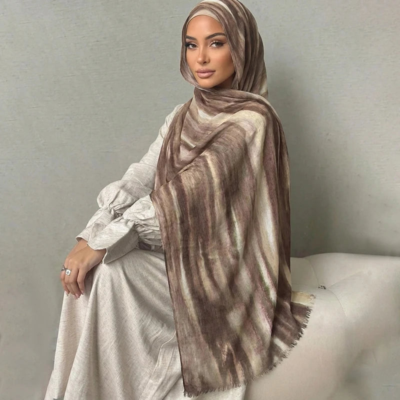 Una mujer vistiendo un pañuelo hijab a rayas marrón y beige sobre un vestido blanco.