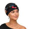 Eine Frau modelliert einen schwarz bedruckten Turban mit Blumenmustern auf Kopf und Schulter.