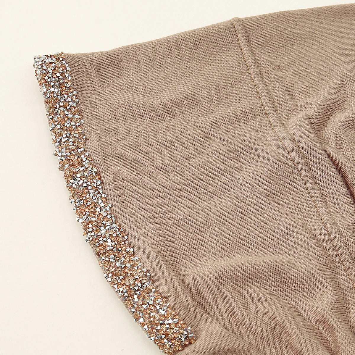 Nahaufnahme eines beigen Hijab-Schals mit funkelnder Strasskante am Rand.