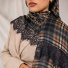 A close-up of a woman wearing a premium printed modal plaid hijab scarf with black lace detailing and earth tones.