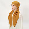 Una mujer vistiendo un pañuelo de lino amarillo mostaza colgado alrededor del cuello, combinado con una blusa blanca.