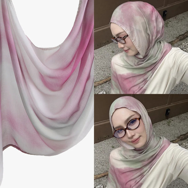 A woman models a watercolor print cotton modal hijab scarf in pink and white tones.