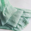 Foulard hijab en coton viscose vert menthe doux avec franges et pompon drapé sur une surface blanche.