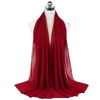 A deep red chiffon hijab scarf draped around a mannequin's neck.