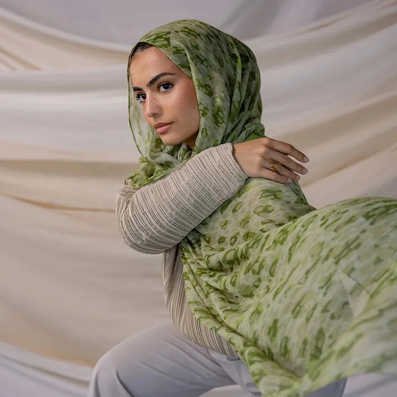 Une femme portant un foulard hijab en polyester doux avec des motifs verts et blancs.