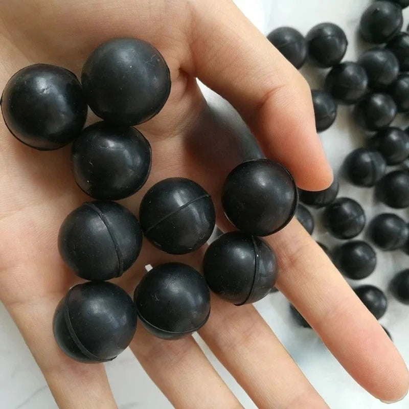 Eine Hand hält mehrere schwarze, industrielle Gummidichtungsbälle unterschiedlicher Größe.