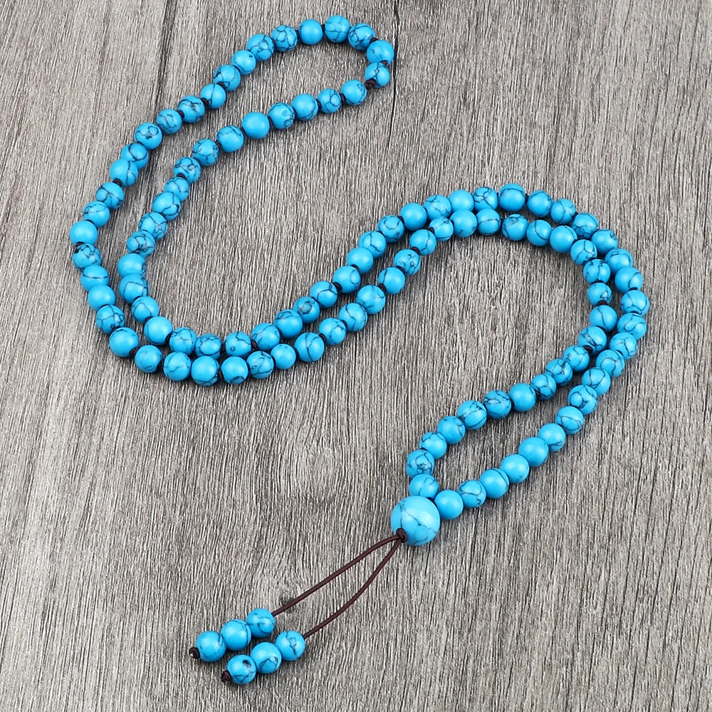 Eine Kette leuchtend blauer Natursteinperlen liegt auf einer grauen Holzoberfläche.