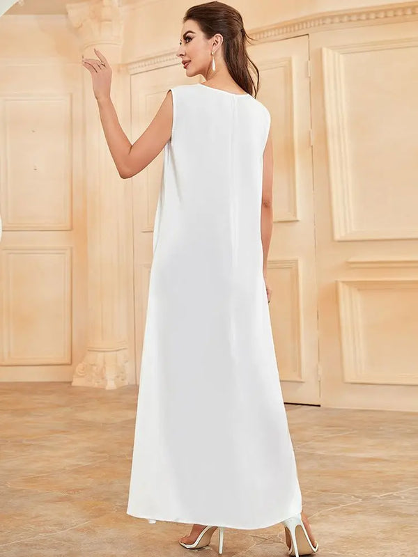 A woman wearing a white flowing modest abaya dress with a high neckline and long sleeves, standing indoors.
