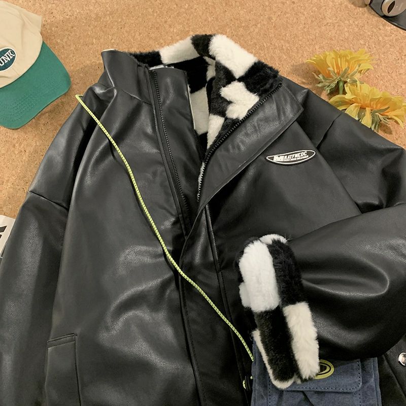 Chaqueta parka de cuero negro con cuello y puños de piel sintética blanca y negra, sobre una superficie de madera.
