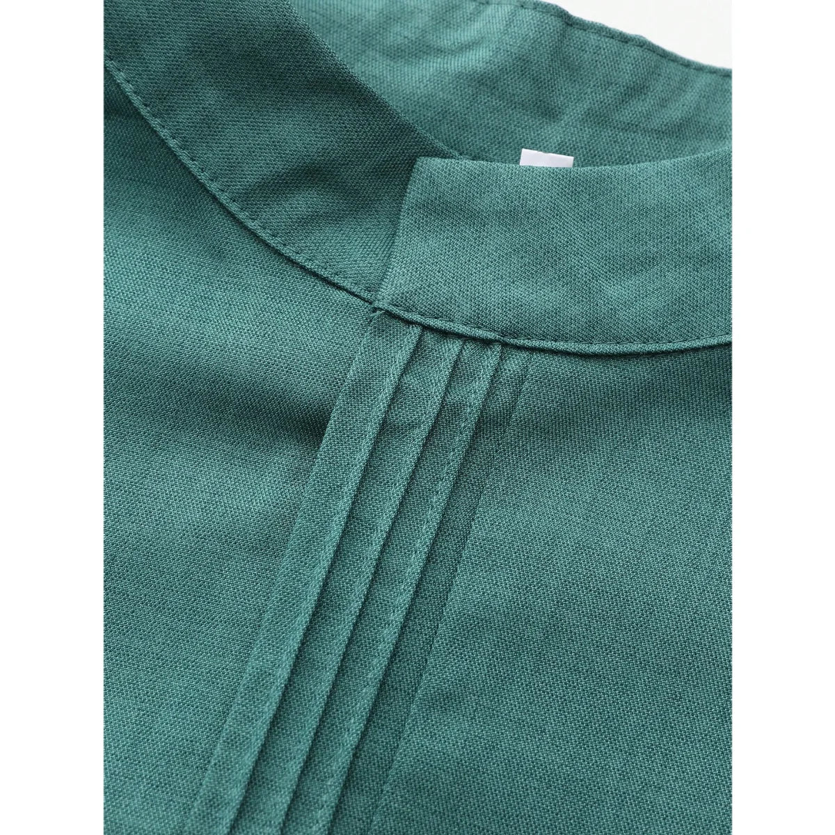 Gros plan sur une robe musulmane masculine bleu sarcelle avec col et plis verticaux.