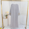 Lange, hellgraue Abaya mit floralen Stickereien in einem goldgerahmten Display.