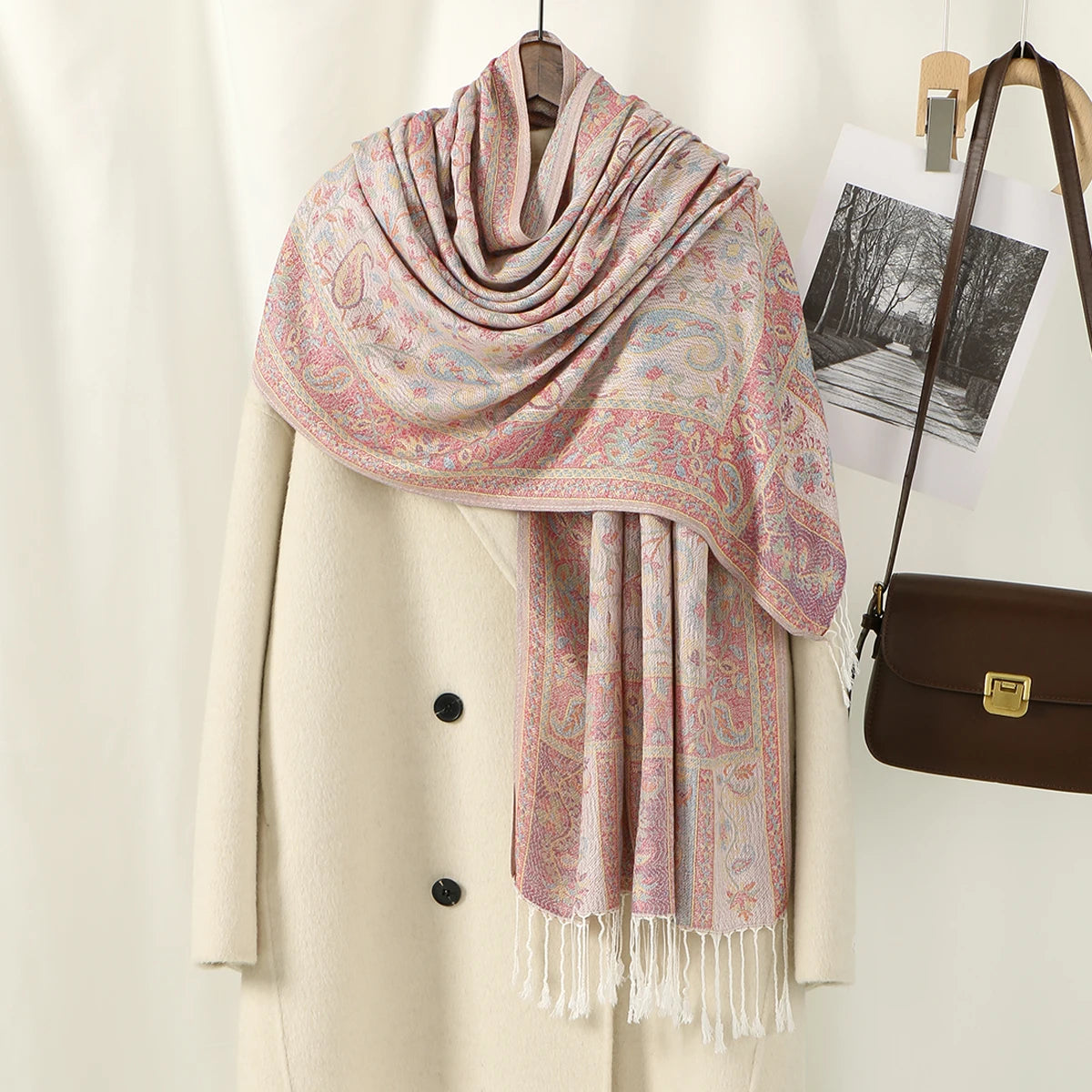 Chal vintage de bordado paisley rosa y beige sobre un abrigo crema.