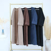 A display of elegant women's abaya trench coats in various neutral and dark colors hanging on a gold rack.