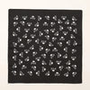 Tissu noir avec un motif répétitif de formes d'insectes ou florales stylisées blanches.