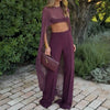 A woman wearing a sheer purple mesh poncho cape and matching trousers standing outdoors.