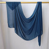 Un foulard hijab de couleur bleu foncé uni drapé sur un cintre en bois.