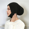 Une femme portant un foulard noir uni, vue de profil sur fond blanc.