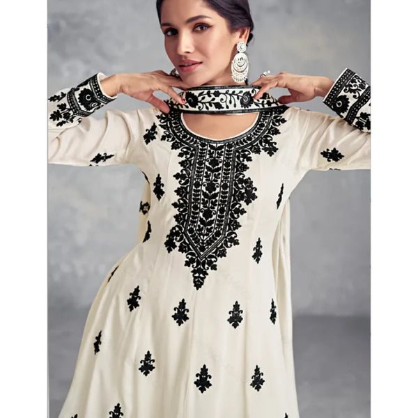 A woman models a cream and black Muslim ethnic two-piece set featuring intricate embroidery and traditional jewelry.