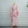 Rosa floral gemusterte Abaya oder Kaftan-Kleid auf einem Mannequin vor einer weißen Paneelwand.